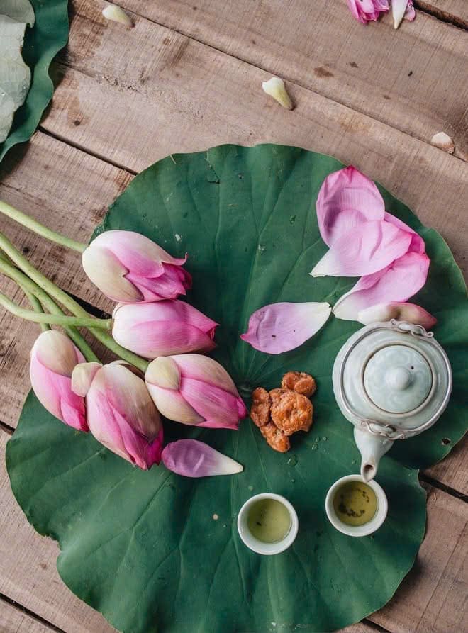 Lá sen, búp sen hồng và ấm trà nhỏ trên bàn gỗ